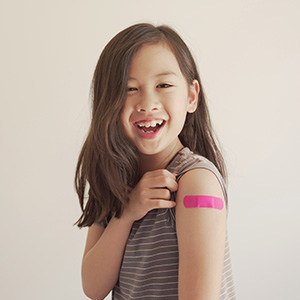Smiling girl showing off bandage after vaccination