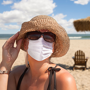 woman wearing mask and hat at beach