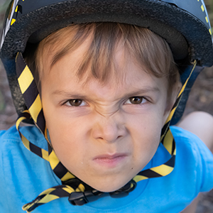 Child in bicycle helmet, making funny face