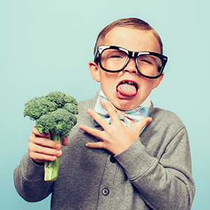 Child holding broccoli, making a faace