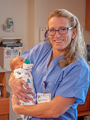 Marian Fuller, MD holding a newborn baby.