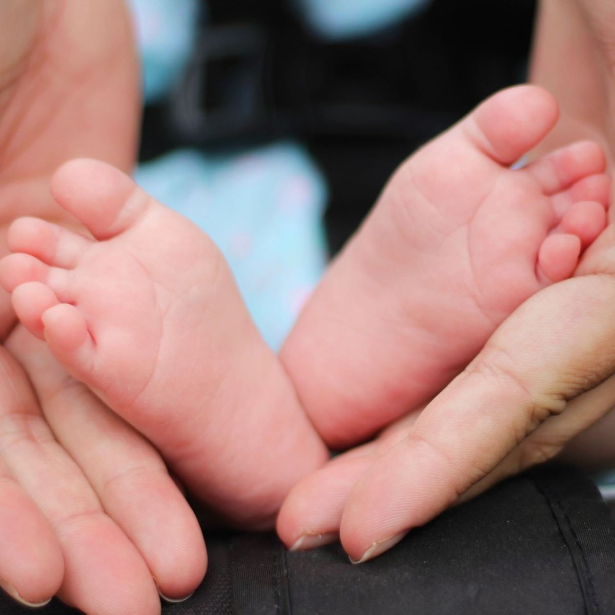 Adult hands cradling baby's feet