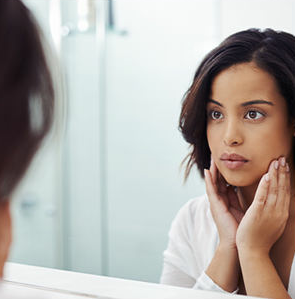 young woman looking at herself in the mirror, concerned
