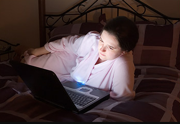 woman on laptop while in bed