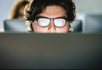 man with glasses staring at computer screen