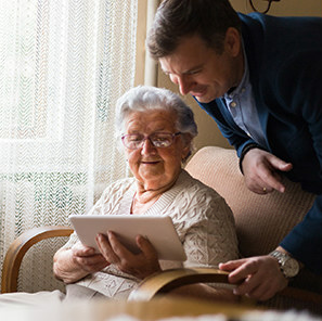 man looking over at a tablet with his elderly moth